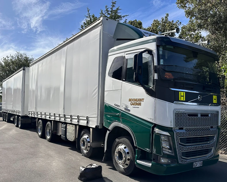 Moonlight Cartage truck parked on tarmac. Blue sky, white canvas on truck trailer units